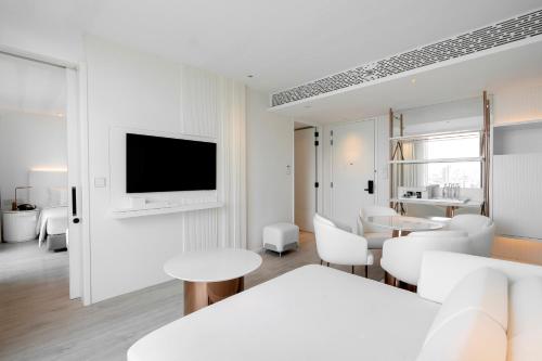 a living room with white furniture and a tv at INNSiDE by Meliá Bangkok Sukhumvit in Bangkok