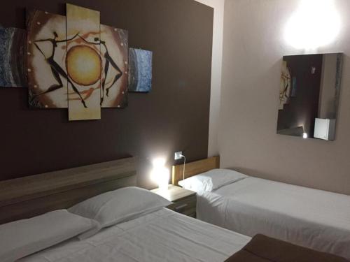 a hotel room with two beds and paintings on the wall at Residence albergo SELF CHECK-IN in Parma