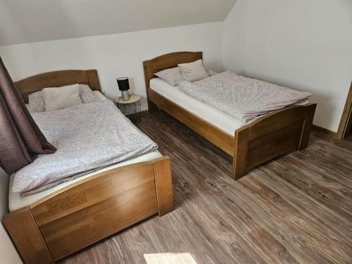 two twin beds in a room with wooden floors at Vinohradnícky domček in Vrádište