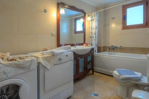 uma casa de banho com uma máquina de lavar roupa, um lavatório e uma banheira em Villa Nikos with Private Pool em Triopetra