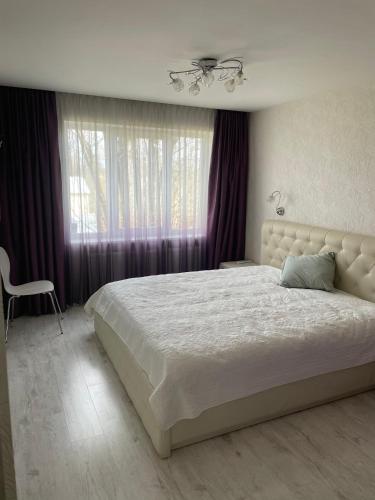a bedroom with a large bed with purple curtains at Emporium Apartments in Rēzekne