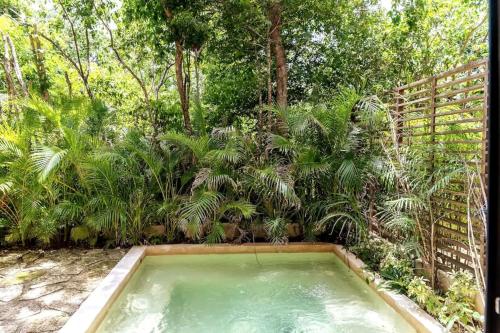 a swimming pool in a garden with trees at Bai-Ha Luxury 103 in Tulum