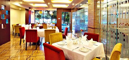 a restaurant with white tables and red chairs at West Park Inn in Dhaka