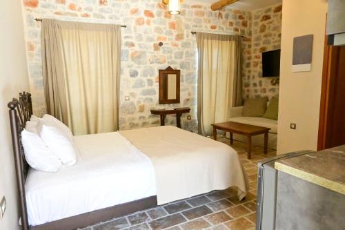 a bedroom with a white bed and a living room at Arapis Rooms & Suites in Áyios Kiprianós