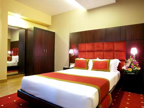 a bedroom with a large white bed with red pillows at West Park Inn in Dhaka