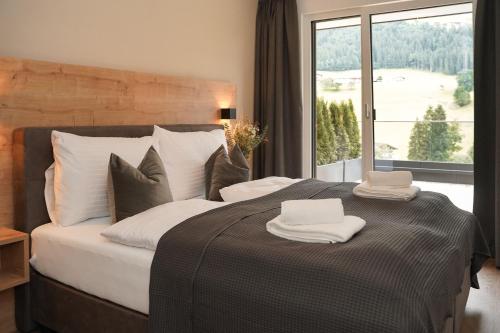 a bedroom with a large bed with two towels on it at Das Lenz by Inncomer in Oberau