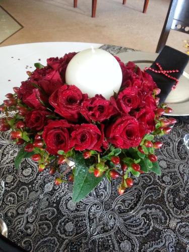 a bouquet of red roses and a candle on a table at Prinshof Manor Guesthouse in Pretoria