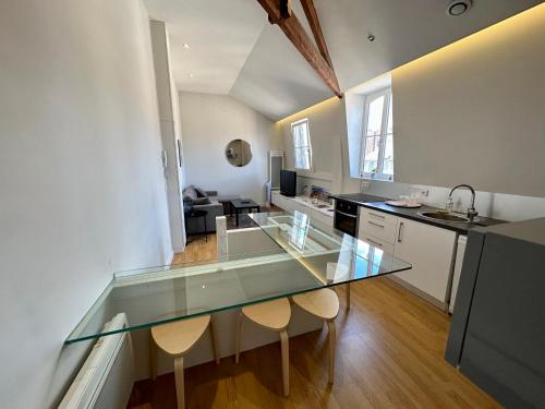 eine Küche und ein Wohnzimmer mit einem Glastisch und Stühlen in der Unterkunft My Little Home - Le Vieux Lille de Danel in Lille