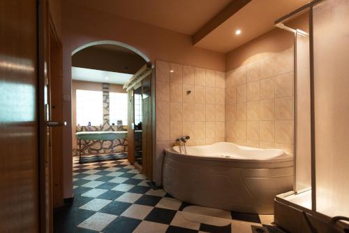 La salle de bains est pourvue d'une grande baignoire et de carrelage. dans l'établissement Hotel Platán, à Zamárdi