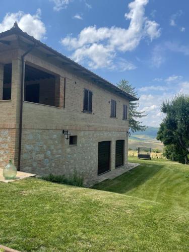 a large stone house with a grass yard at L’ Aia del Principe in Montepulciano