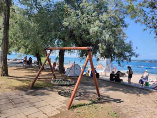 a swing set in a park next to the beach at Apartma-studio Barbara in Žusterna