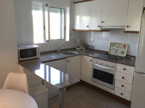 cocina con armarios blancos y encimera en Nice 4 Person apartment residence La Sella Golf Resort Marriott Denia, en Pedreguer