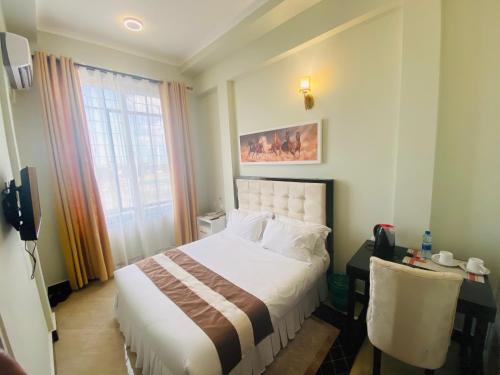 Cette chambre comprend un lit, un bureau et une fenêtre. dans l'établissement Diary Hotel, à Dar es Salaam