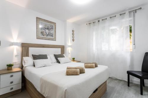 ein weißes Schlafzimmer mit einem großen Bett und einem Stuhl in der Unterkunft Sur Suites Principe in Fuengirola