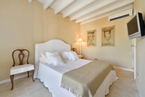 a bedroom with a bed and a tv and a chair at Dalt Vila House in Ibiza Town