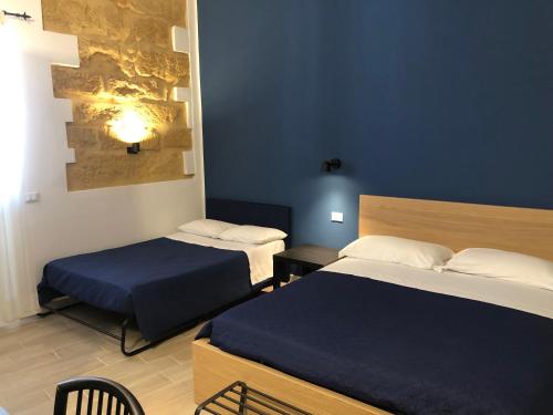 a hotel room with two beds and a table and chairs at Kalé Atenea in Agrigento