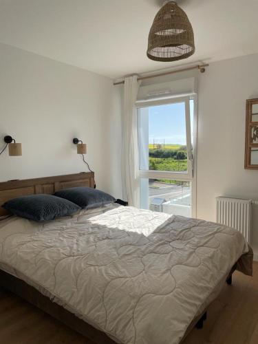 une chambre avec un grand lit et une fenêtre dans l'établissement Le Wim’bowé, à Wimille