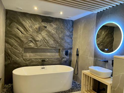 a bathroom with a tub and a sink and a mirror at Clockhouse Cottage in Saulkrasti