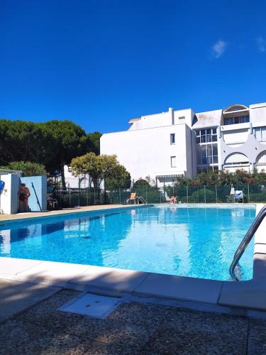 une grande piscine bleue devant un immeuble dans l'établissement ALAMANDA STUDIO LE GRAU DU ROI -, au Grau-du-Roi