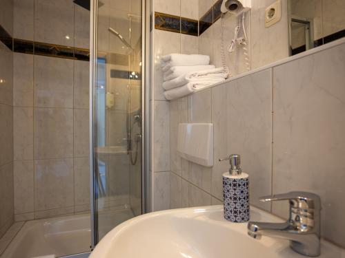 a bathroom with a sink and a glass shower at Hotel Mauritius in Crimmitschau