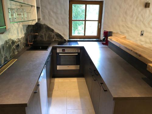 a kitchen with a counter with a stove and a window at Pointhäusl in Pfarrwerfen