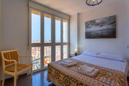 een slaapkamer met een bed, een stoel en ramen bij Cielo gaditano in Cádiz