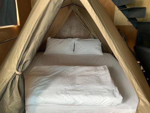 a bed in a tent with white sheets and pillows at Funzpace in Hengchun