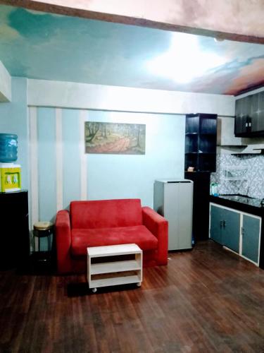 uma sala de estar com uma cadeira vermelha e uma cozinha em Apartemen Cibubur village by ipol em Cibubur