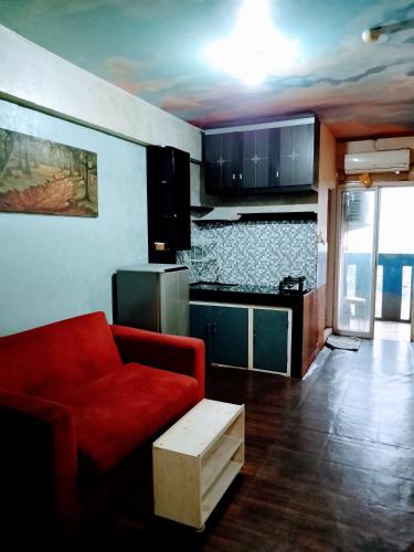 a living room with a red couch and a kitchen at Apartemen Cibubur village by ipol in Cibubur