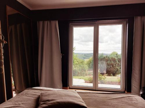 a bedroom with a bed and a large window at Les amoureux du vrai in Malmedy