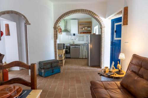 a living room with a couch and a kitchen at Sunrise Monsaraz Blue - Casa com 2 quartos Jardim in Monsaraz