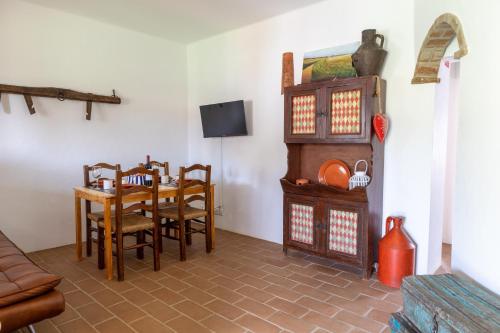 a dining room with a table and chairs and a tv at Sunrise Monsaraz Blue - Casa com 2 quartos Jardim in Monsaraz