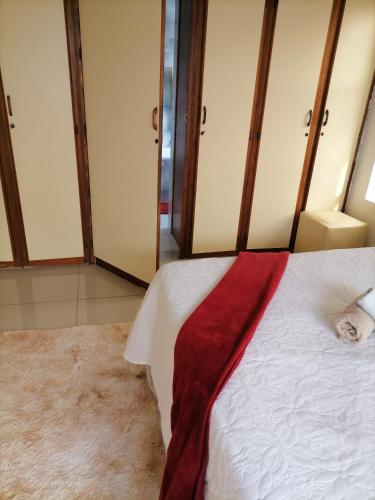 - une chambre avec un lit blanc et une couverture rouge dans l'établissement Glenwood, à Durban