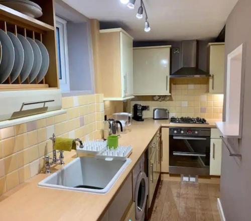 a kitchen with a sink and a stove at Haven Cottage, Golden Square in Cromer
