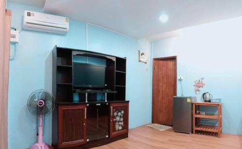 a living room with a flat screen tv and a fan at Inthanon Lao-Ju House in Chom Thong
