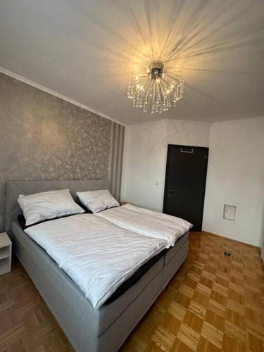 1 dormitorio con 1 cama grande y lámpara de araña en Freundliche Wohnung Nähe Weinstraße für 5 Personen, en Wagna