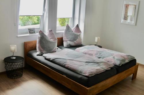 1 cama con almohadas en una habitación con 2 ventanas en Ferienwohnung Faber, en Gerolstein