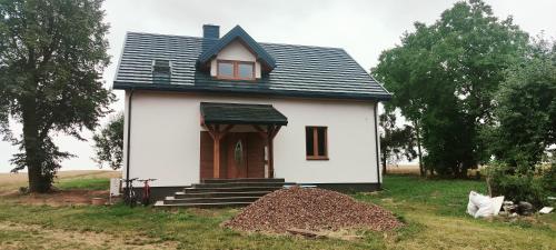 a small white house with a gambrel roof at Ranczo Bosikowo in Kłyżówka
