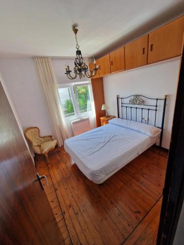 1 dormitorio con 1 cama, 1 silla y 1 lámpara de araña en APARTAMENTO SUJARRERA, en Villacarriedo