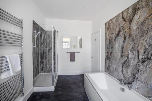 uma casa de banho com uma banheira e uma parede de pedra em Great Location Free Parking Near Tamar Bridge em Saltash