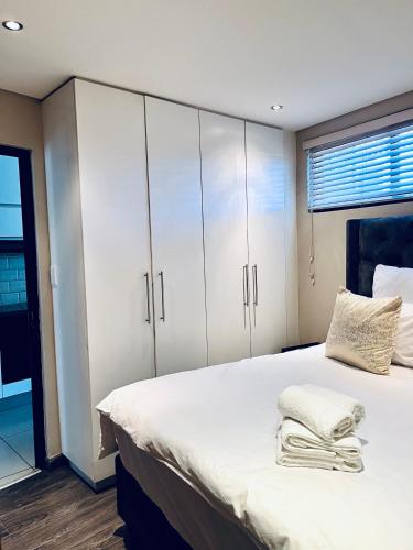 a bedroom with a large bed with white cabinets at ModernLuxe Apartment in Windhoek