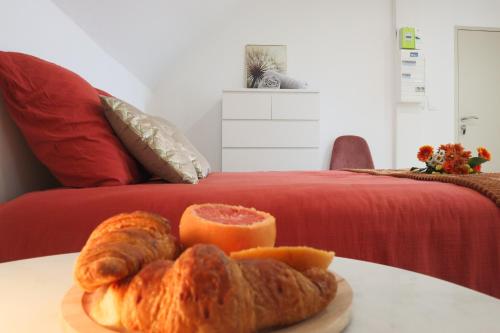 a plate of bread and an orange on a table next to a bed at Le Cocon, Paisible & Doux in Wahlbach