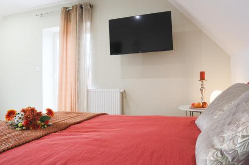 a bedroom with a red bed with a television on the wall at Le Cocon, Paisible & Doux in Wahlbach