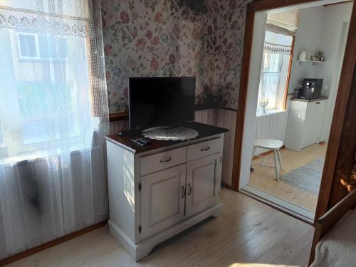 uma sala de estar com uma televisão num armário e um espelho em Wiedemanni Apartment em Haapsalu