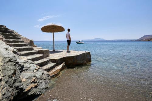 a man standing on a dock with an umbrella at Beachfront Villa in Crete - Epavli Luxury Villa in Agia Pelagia