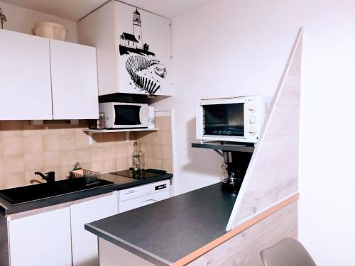 a kitchen with white cabinets and a black counter top at ALAMANDA STUDIO LE GRAU DU ROI - in Le Grau-du-Roi