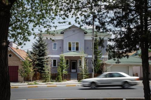 a white car driving down a street in front of a house at People Guest House in Bishkek