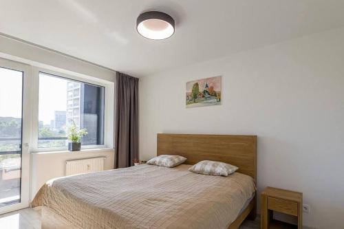 een slaapkamer met een bed en een groot raam bij Urban apartment with free parking in Bratislava