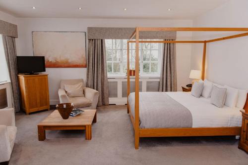 una camera d'albergo con letto, divano e TV di Woodlands Hotel a Leeds
