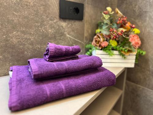 a pile of purple towels sitting on a shelf with flowers at Ca' Filipet in Torri del Benaco